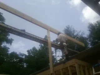 Carpenter setting a ridge beam over a new addition frame — Ice Dam Removal by Roofing Brothers in Coleman