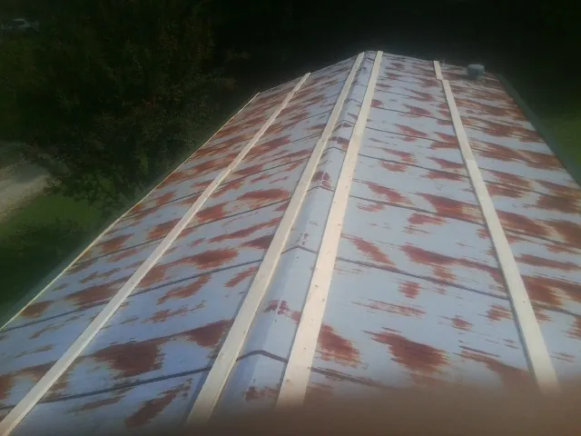 Rusted metal roof panels with new wood purlins before replacement — Storm Damage Roof Repair in Coleman by Roofing Brothers