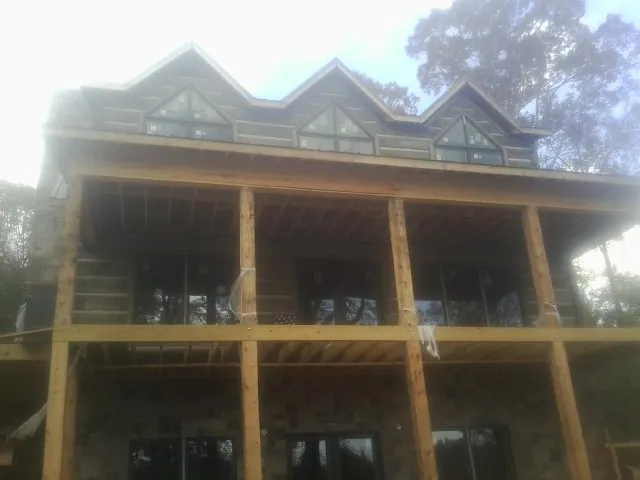 Dormers and porch framing on a large log home under construction — Roof Coating work by our crew in Coleman
