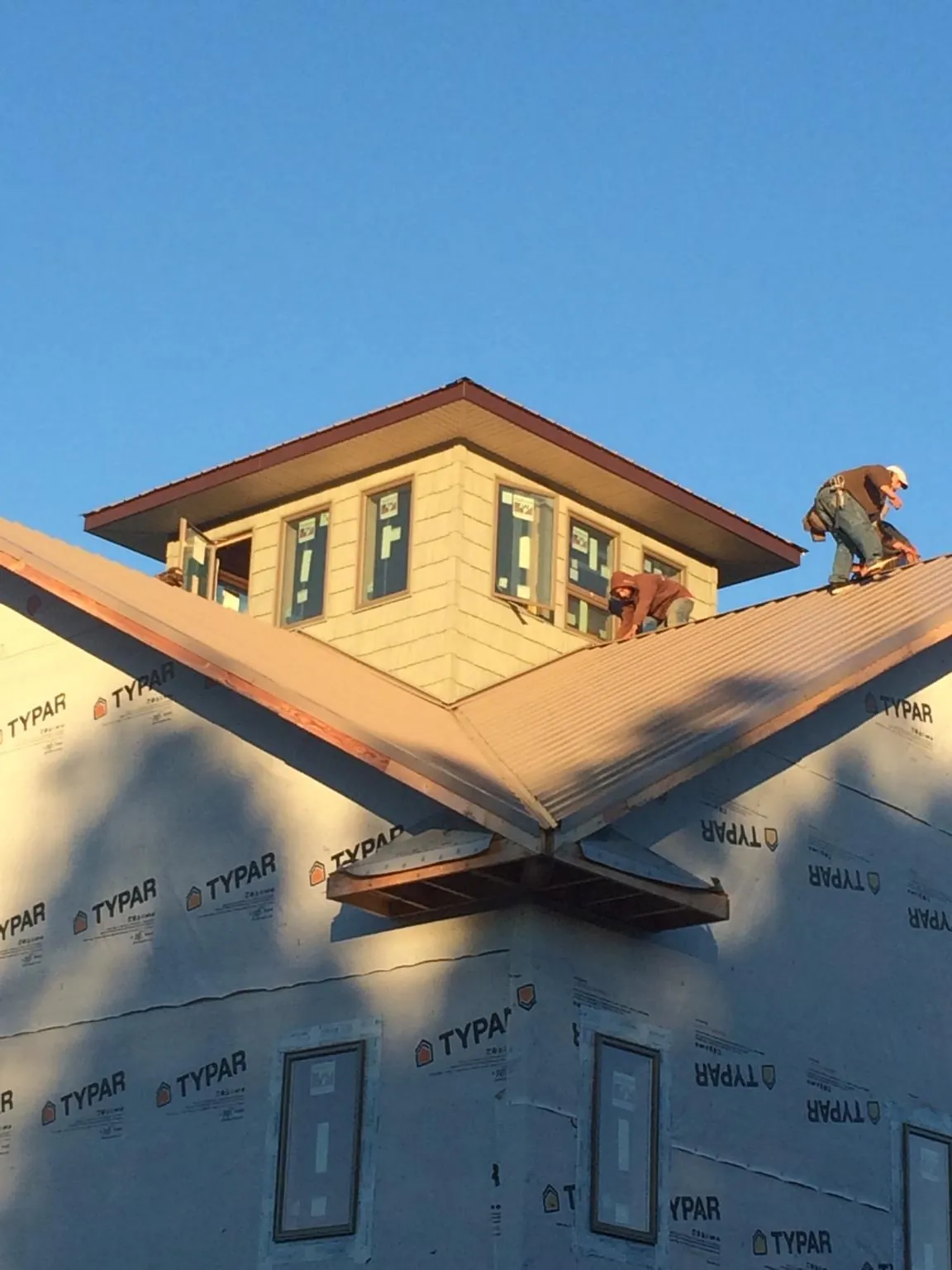 Roofers working around a rooftop cupola on a new metal roof at sunset — Roof Waterproofing in Coleman by Roofing Brothers